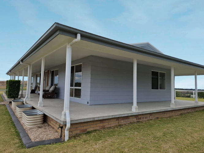Exterior of a house with grey walls and white posts.