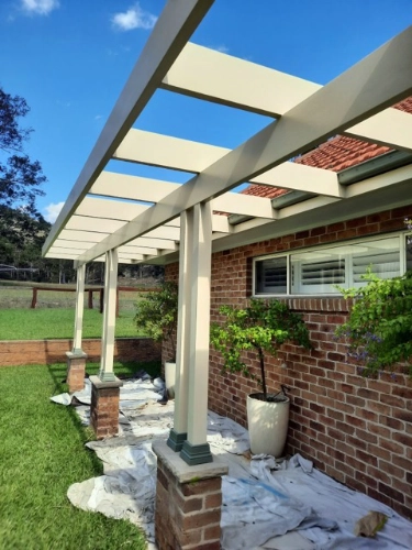 Pergola posts in the process of being painted cream.