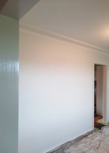 White wall drying. Drop sheets cover the floor.